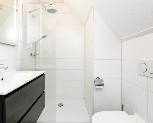 helles badezimmer mit dunklem waschbecken schubladen dusche klo und spiegel