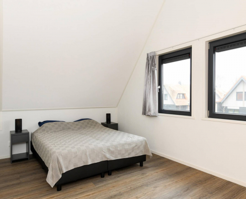helles schlafzimmer mit durchsichtigen fenstern schwarzem rand holzboden und weißen wänden